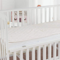 An organic cotton waterproof mattress pad on a crib mattress.