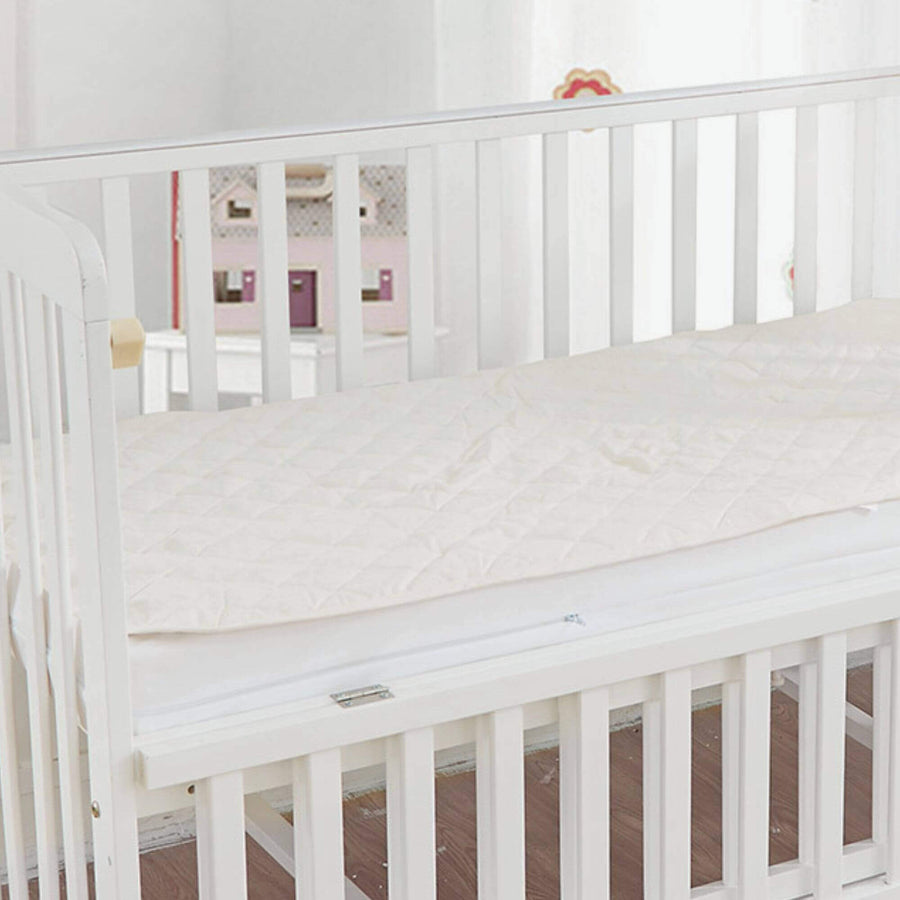 An organic cotton waterproof mattress pad on a crib mattress.