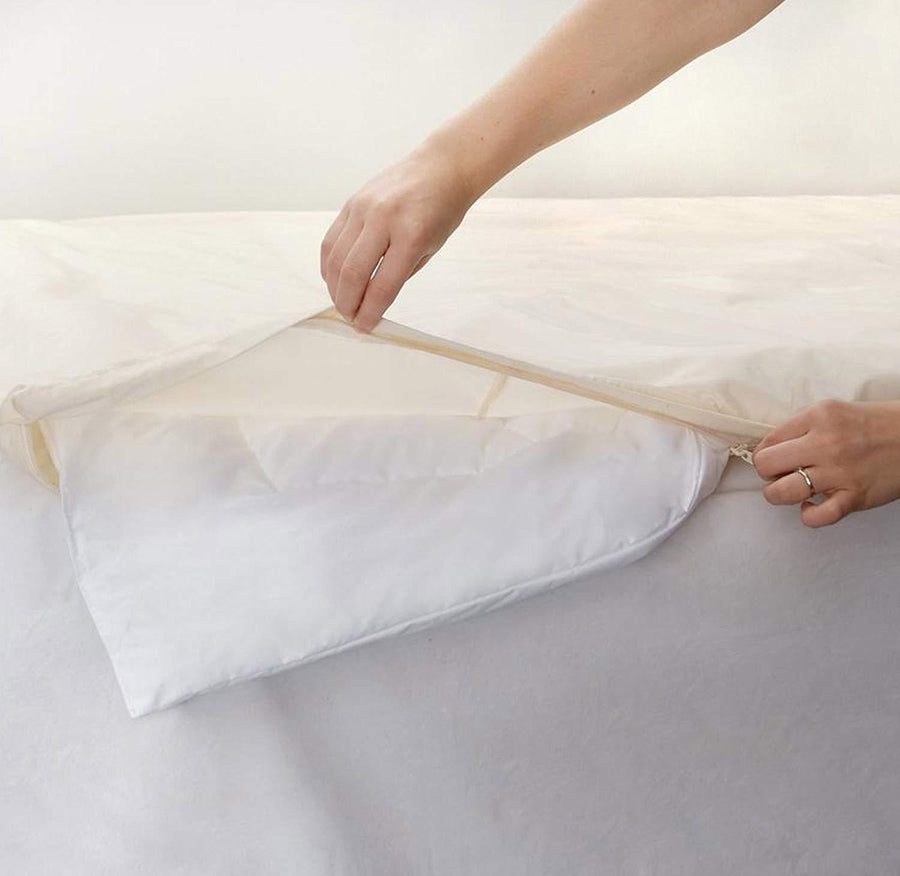 Hands closing the cream AllergyCare organic cotton cover around a white comforter